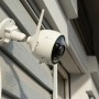 Telecamera di videosorveglianza bianca con antenna montata su una parete di casa.