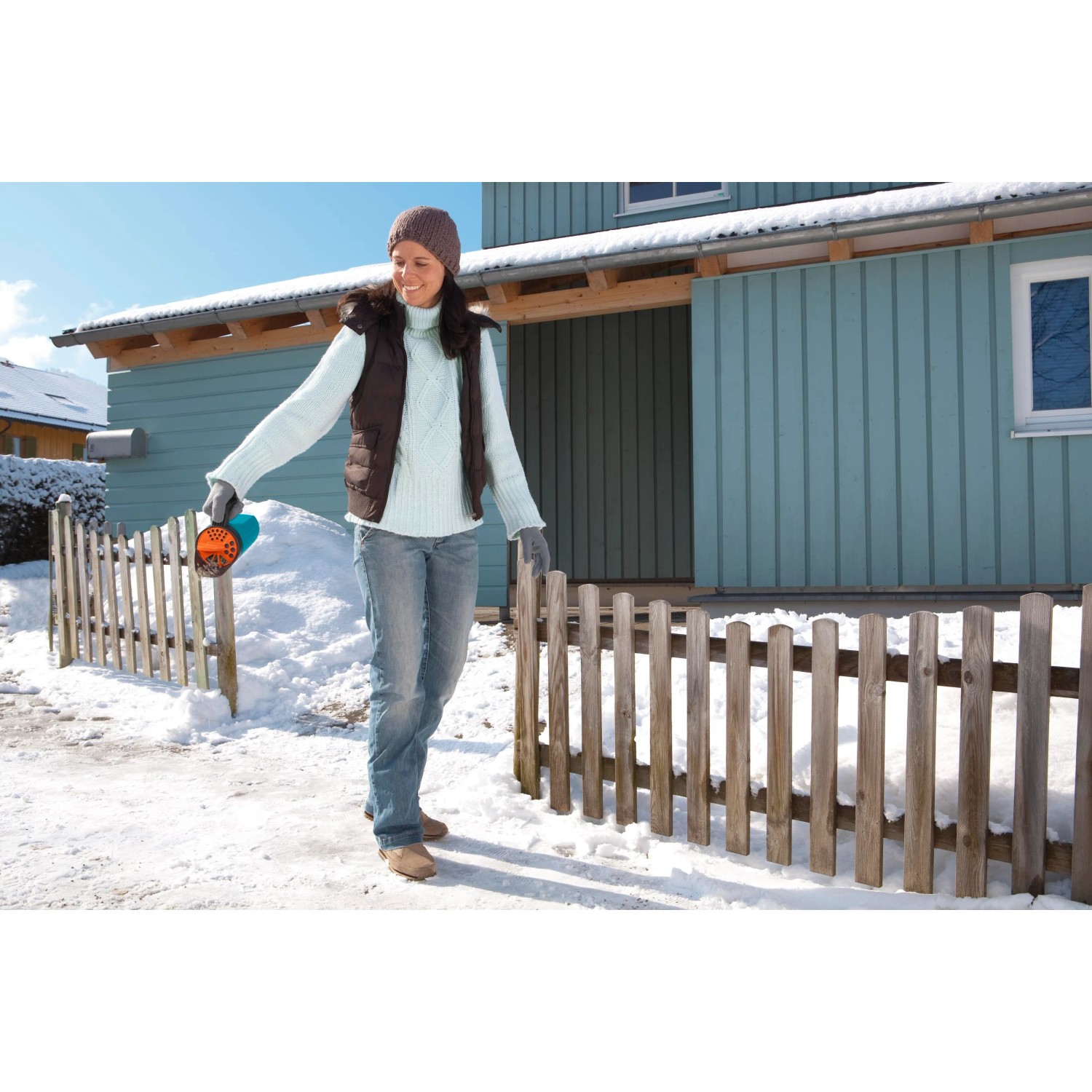 Donna che usa uno spargitore Gardena Kleinstreuer S turchese in inverno per spargere sale.