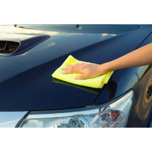 Panno giallo pulisce il cofano di un'auto. Panni e spugne.