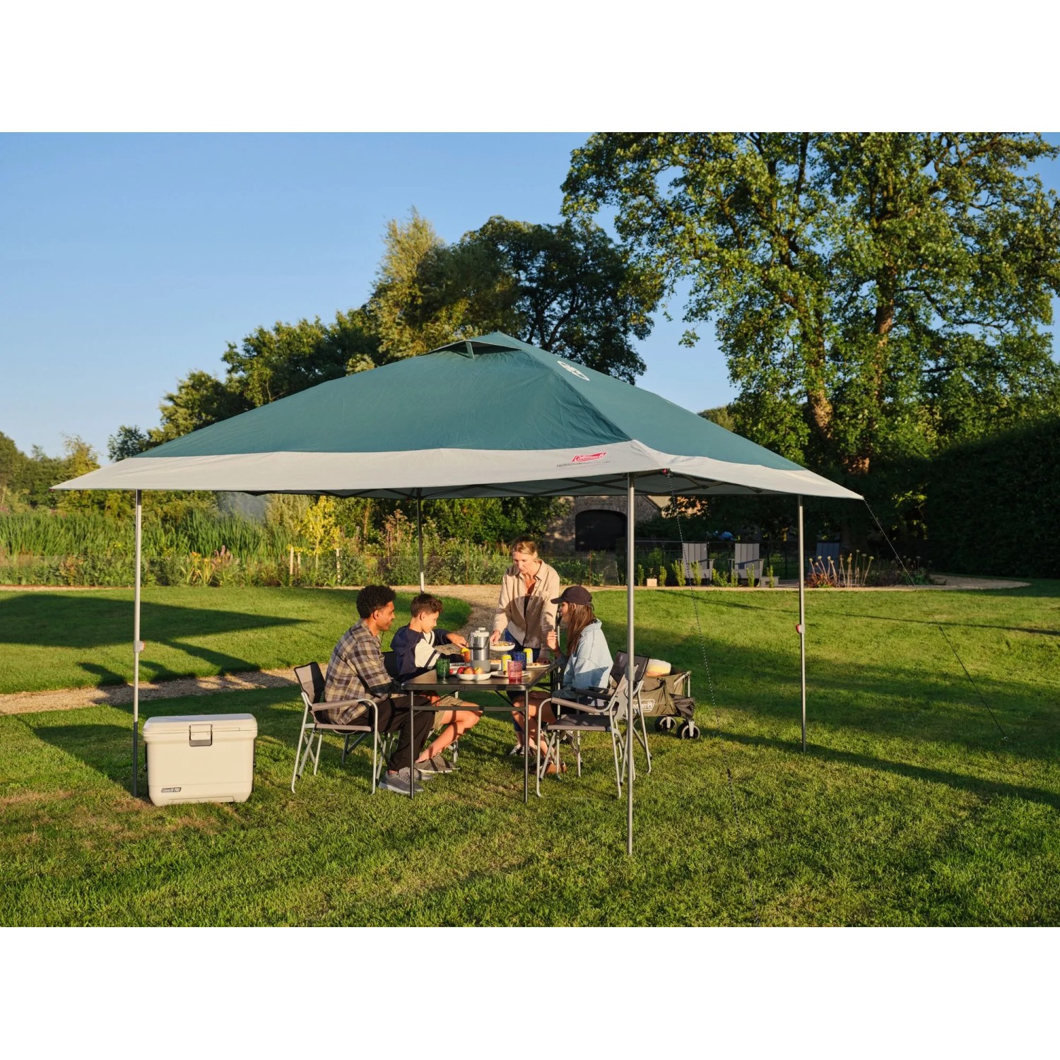 Coleman FastPitch OnePush Shelter L, verde e bianco, con famiglia in campeggio in giardino.