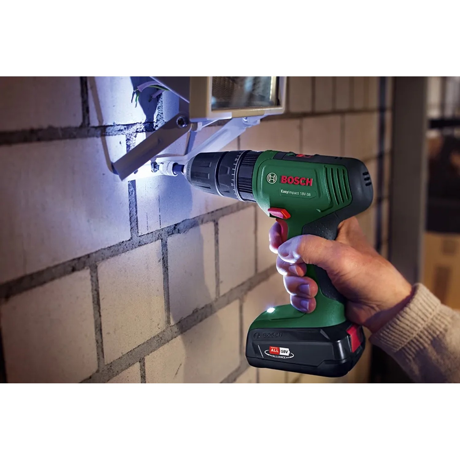 Avvitatore a percussione a batteria Bosch che fora un muro di mattoni, con batteria e luce LED.