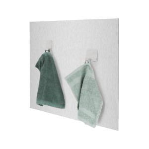 Due asciugamani (verde e verde chiaro) appesi a ganci davanti a un paraschizzi da cucina.