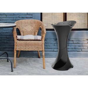 Tavolino da giardino/portafiori nero accanto a sedia in rattan come decorazione da giardino.