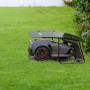 Robot tagliaerba t.b.t. grigio con stazione di ricarica su prato.