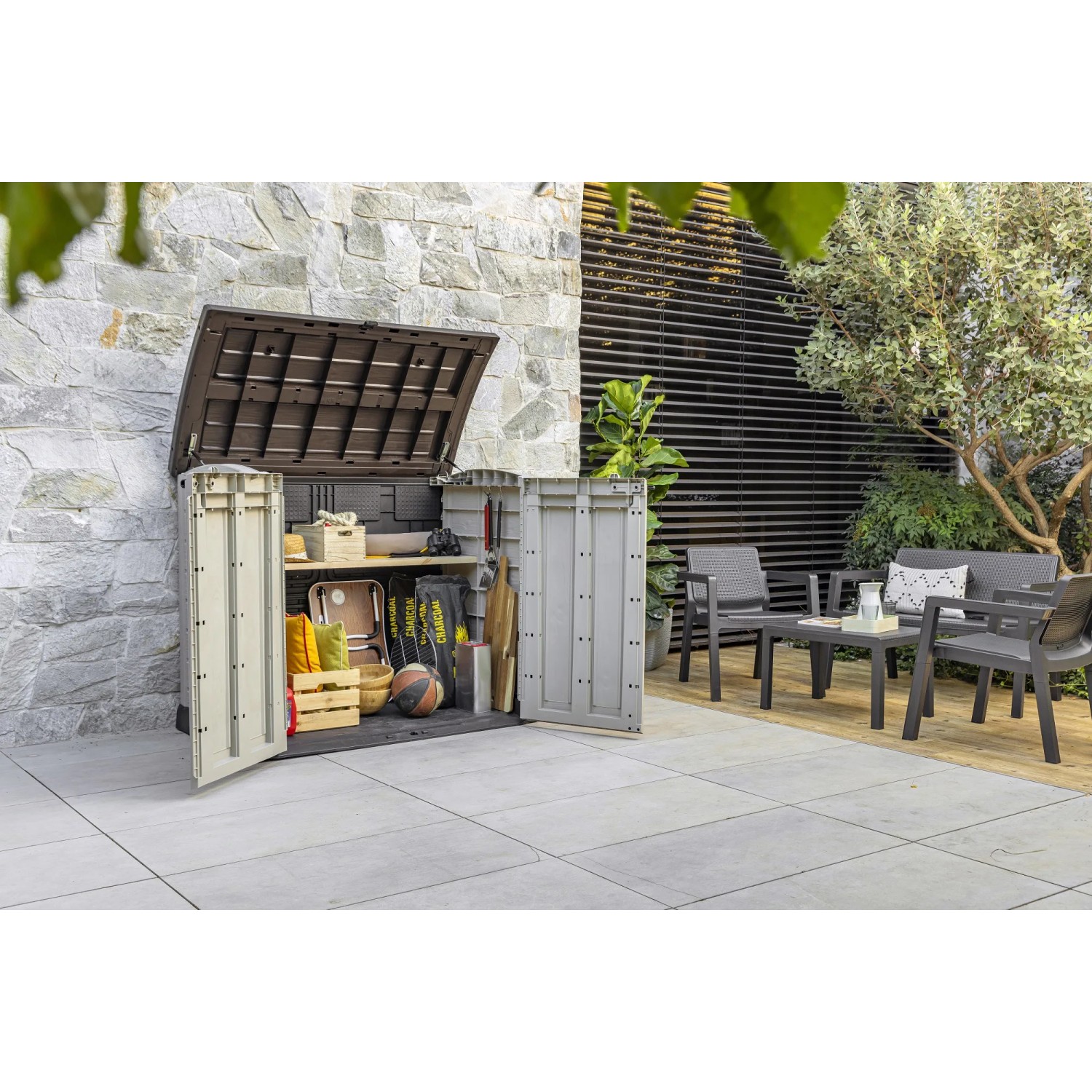 Box universale t.b.t. grigia aperta in giardino con attrezzi da giardinaggio e attrezzature sportive.