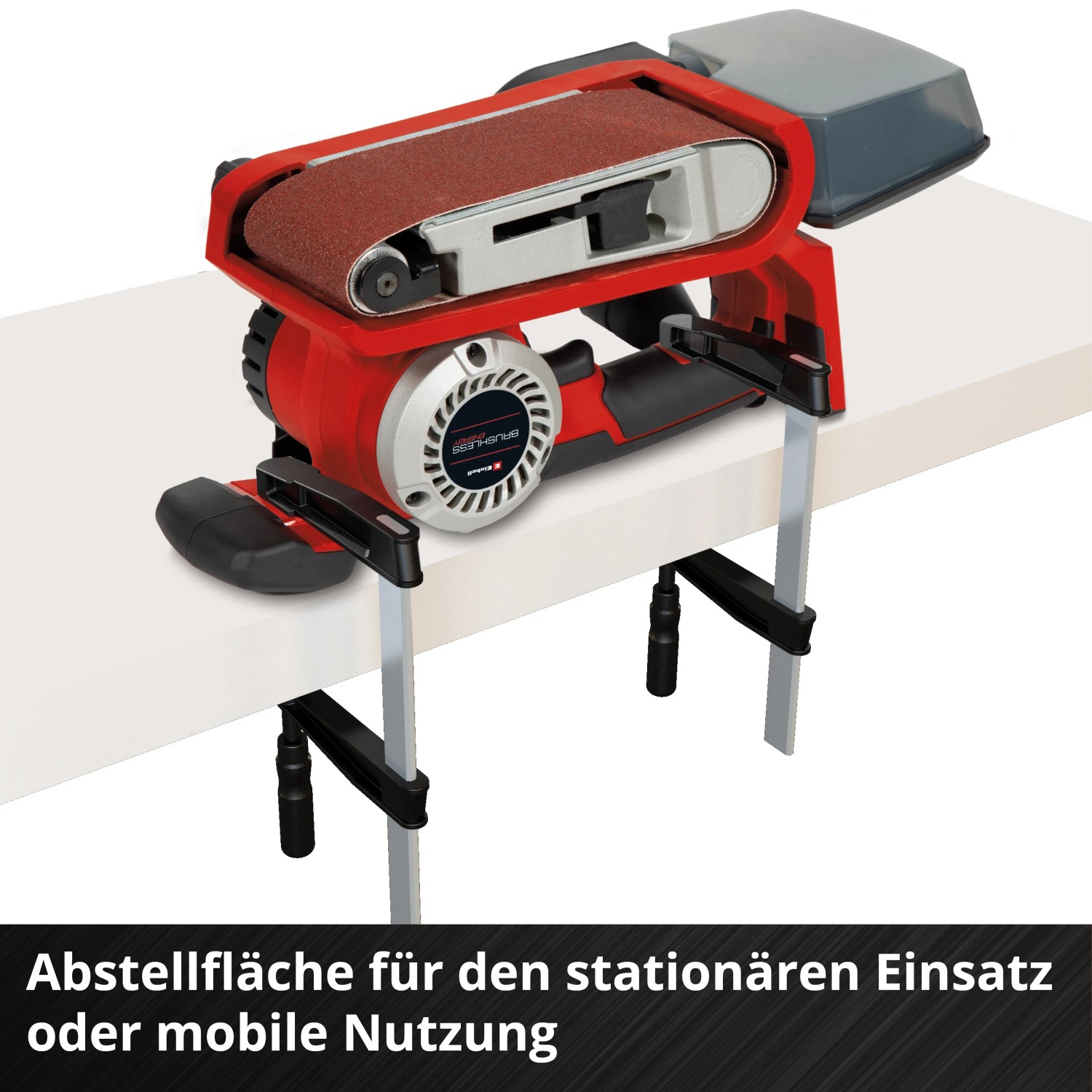 Levigatrice a nastro a batteria Einhell TP-BS 18/457 Li BL Solo con scatola raccoglipolvere e nastri abrasivi su banco.