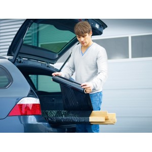 Uomo che imballa legno con pellicola estensibile nera LUX nel bagagliaio di un'auto.