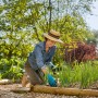 Donna che pianta in giardino con guanti Gardena per piantare e terreno 10/XL.