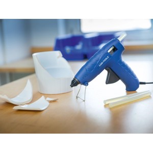Set pistola per colla a caldo LUX 100W con stick di colla e ceramica rotta sul tavolo.