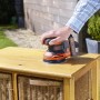 Levigatrice eccentrica a batteria Black+Decker BDCROS18N mentre leviga un comò di legno all'aperto.