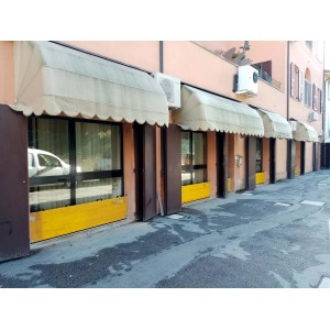 Facciata di edificio con tende da sole e barriere di protezione dalle inondazioni.