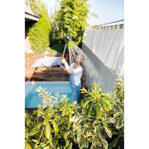 Donna che annaffia le piante con un irrigatore da giardino verde. Lancia per irrigazione in uso.
