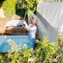 Donna che annaffia le piante con un irrigatore da giardino verde. Lancia per irrigazione in uso.