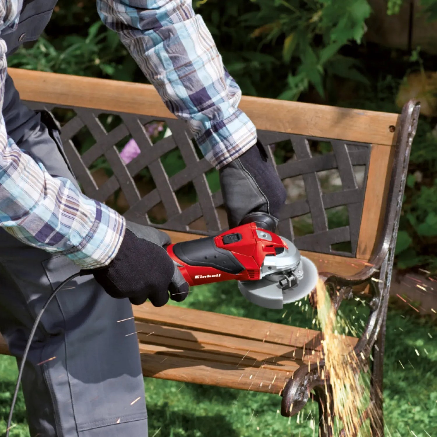 Smerigliatrice angolare Einhell TC-AG 115 in uso per levigare una panca da giardino. Scintille visibili.