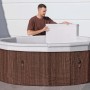 Vasca idromassaggio rotonda t.b.t. effetto legno con uomo che applica la copertura.