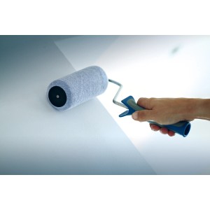 Mano che dipinge la parete con rullo LUX da 25 cm con impugnatura morbida nera e blu.