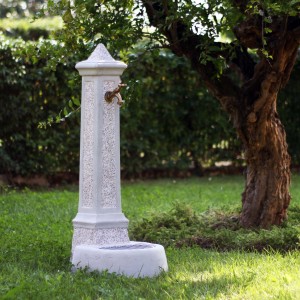 Colonna decorativa per fontana da giardino con rubinetto in ambiente esterno.