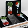 Set di 2 coperture per piano cottura Wenko Caprese con pomodori, mozzarella e basilico su sfondo nero.