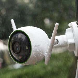 Telecamera di videosorveglianza t.b.t. bianca con antenne sotto la pioggia.