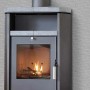 Stufa a legna con rivestimento grigio e piano in pietra per riscaldamento interno.