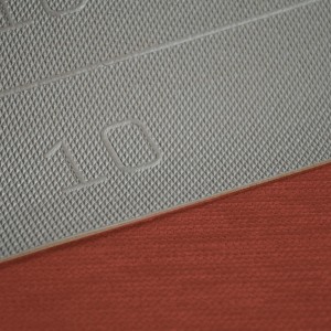 Dettaglio di uno zerbino/tappeto da cucina grigio con il numero 10 e bordo rosso.