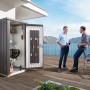 Armadio da giardino Biohort Gr. 90 aperto, grigio scuro, con barbecue e accessori, due uomini sullo sfondo.