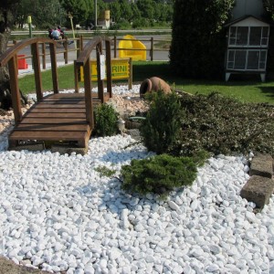 Ciottoli decorativi bianchi (t.b.t.) in giardino con ponte e piante.