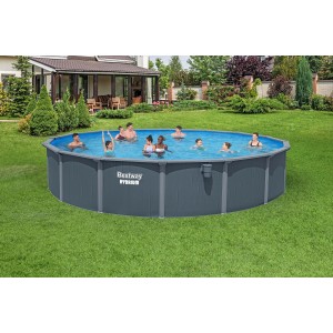 Piscina fuori terra rotonda con rivestimento grigio e bagnanti in giardino.