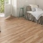 Pavimento laminato Comfort Quercia Royal Elm 7 mm installato in camera da letto con letto e porta-finestra aperta.
