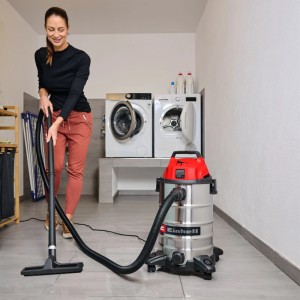 Donna pulisce pavimento con aspirapolvere Einhell TC-VC 3055 S con serbatoio in acciaio inox da 30 L.