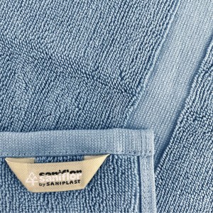 Dettaglio di un tappeto da bagno t.b.t. azzurro con etichetta.