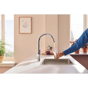 Miscelatore cucina Grohe Blue Pure: rubinetto argento riempie bicchiere con acqua filtrata.