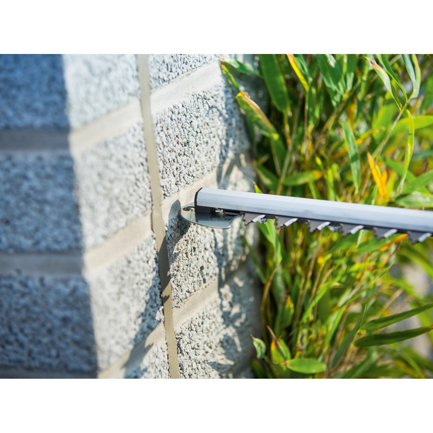 Dettaglio del tagliasiepi telescopico a batteria LUX A-HS-20/51T mentre taglia una siepe.