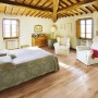 Pavimento in parquet t.b.t. chiaro in una camera da letto con soffitto con travi in legno.