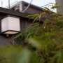 Lampada da parete solare a LED Lutec Doblo color antracite con sensore di movimento su parete in legno.