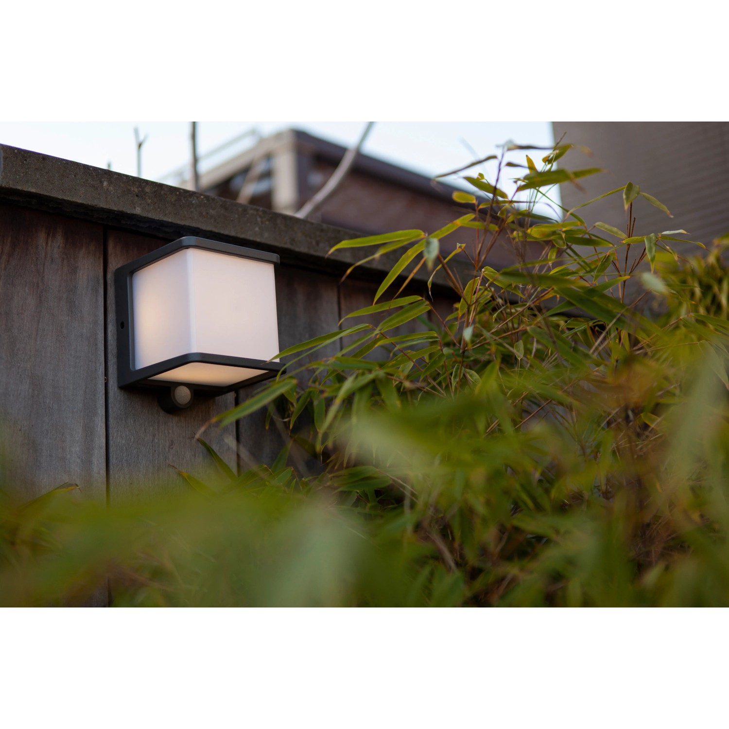 Lampada da parete solare a LED Lutec Doblo color antracite con sensore di movimento su parete in legno.