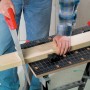 Banco da lavoro e di serraggio in uso: trave di legno in fase di taglio.