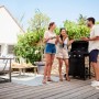 Scena con barbecue a gas t.b.t. in giardino con tre persone che grigliano.