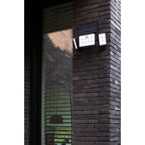 Lampada solare a LED Lutec Tuda nera con 3 luci su un muro di mattoni.