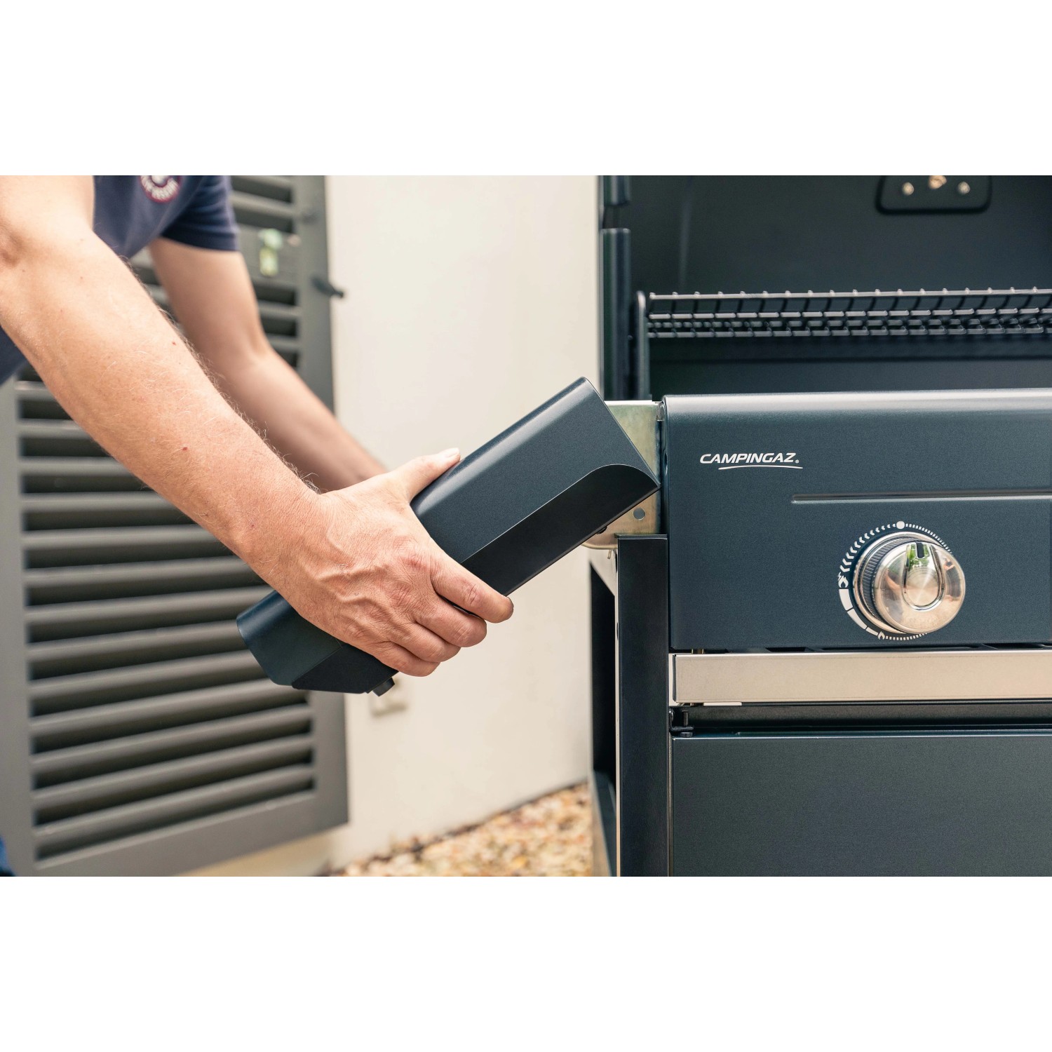 Persona inserisce la batteria nel barbecue a gas. Accessorio barbecue.