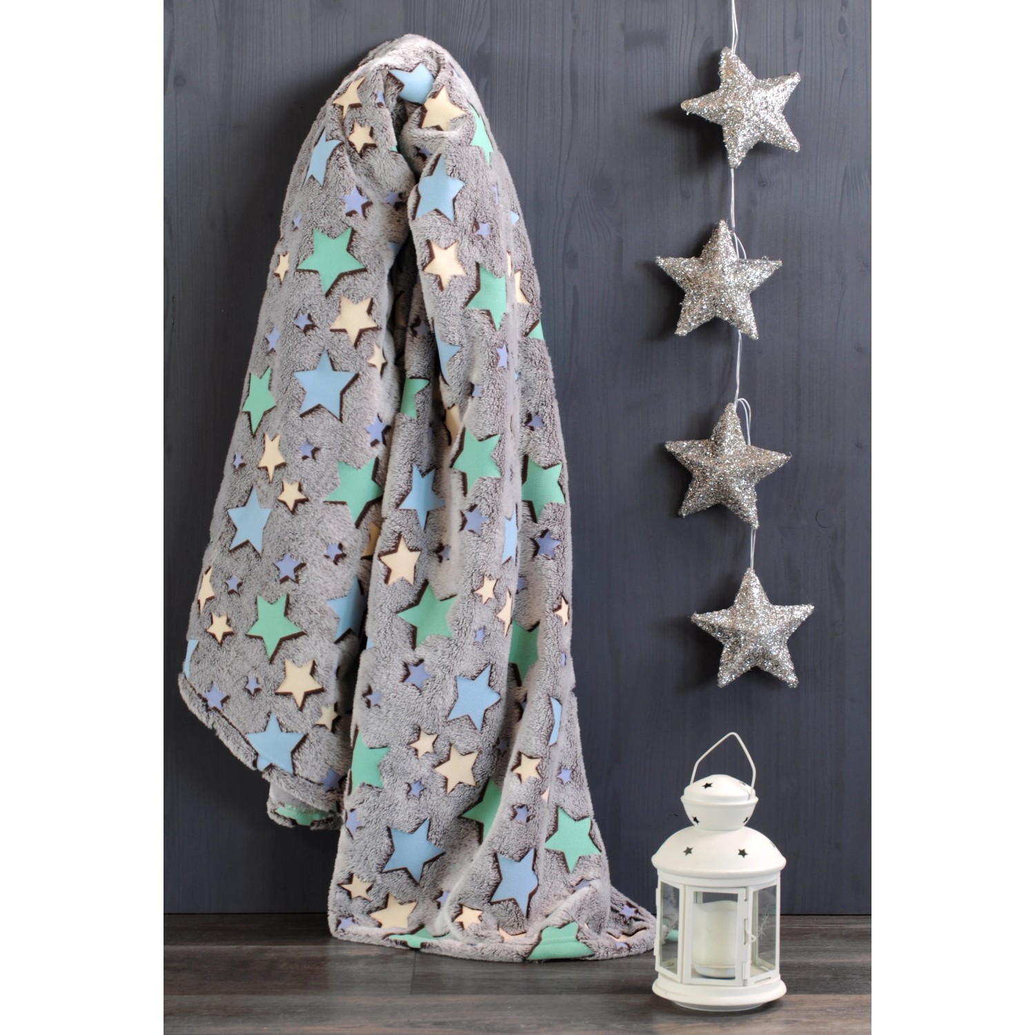 Coperta grigia con motivo a stelle, abbinata a stelle decorative e lanterna.