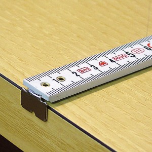 Dettaglio di un metro pieghevole bianco su una superficie di legno.