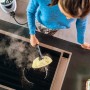 Donna pulisce il piano cottura con il pulitore a vapore Kärcher SC 5 EasyFix Iron Plug.