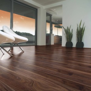 Pavimento laminato t.b.t. effetto legno scuro in soggiorno con sedie e piante.