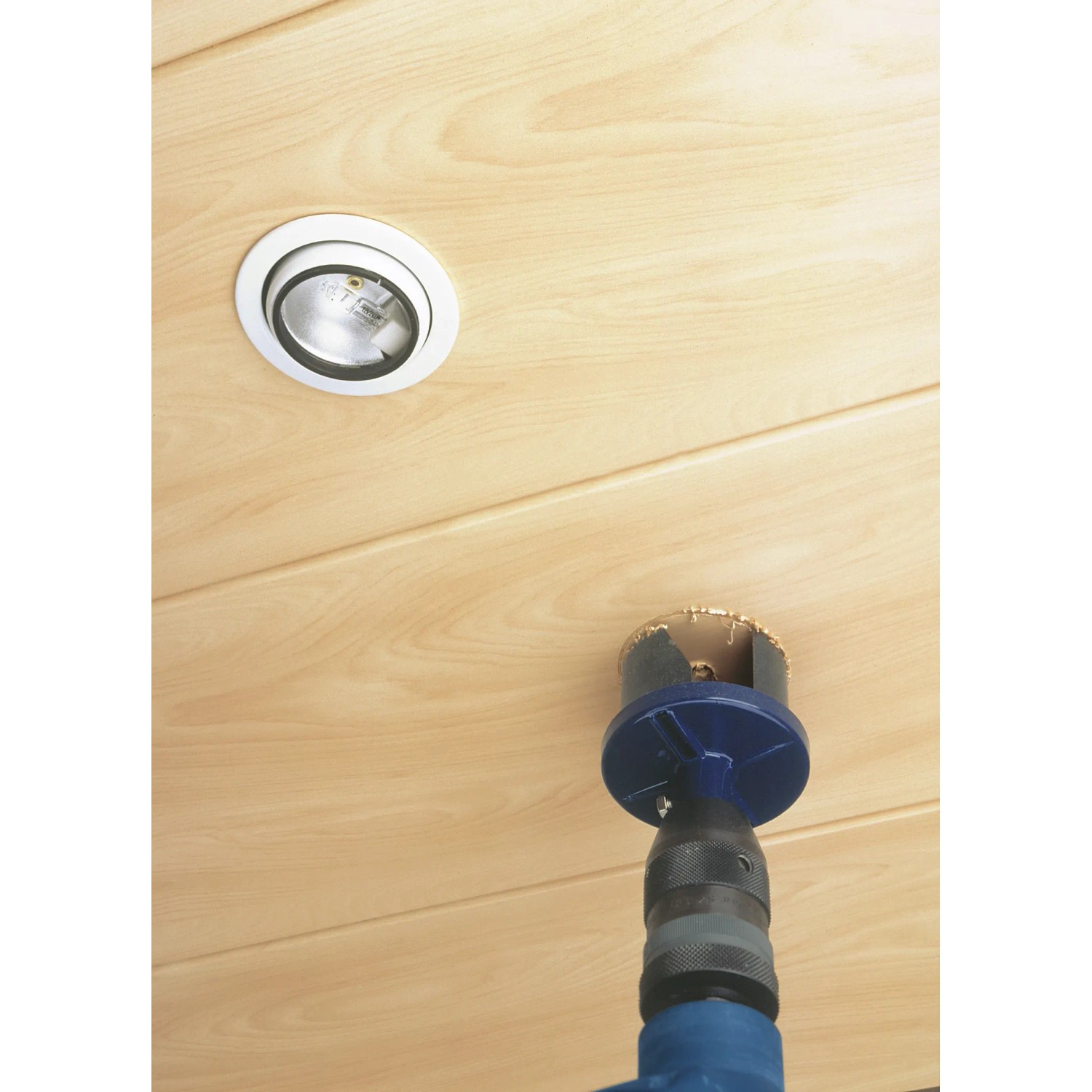 Set di seghe a tazza in uso: Foratura di un foro in un soffitto di legno con lampada.