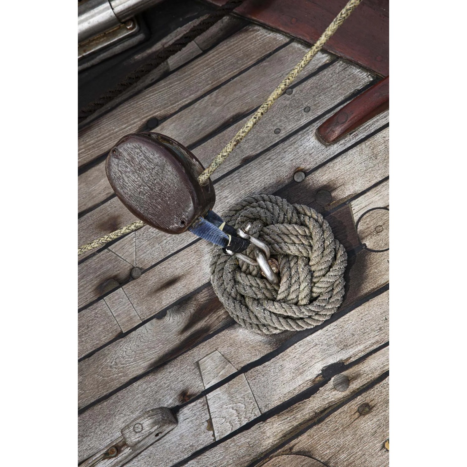 Dettaglio di cordame e bozzello su un ponte di legno. Accessori nautici.