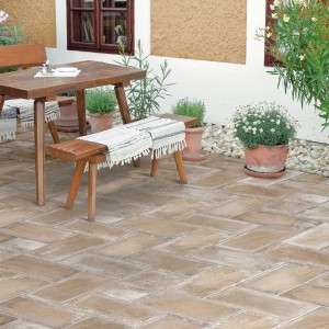 Piastrelle per pavimentazione esterna rettangolari marroni con area salotto e piante.