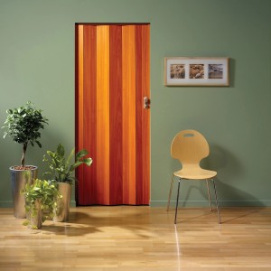 Porta a soffietto in legno arancione in stanza con piante e sedia.