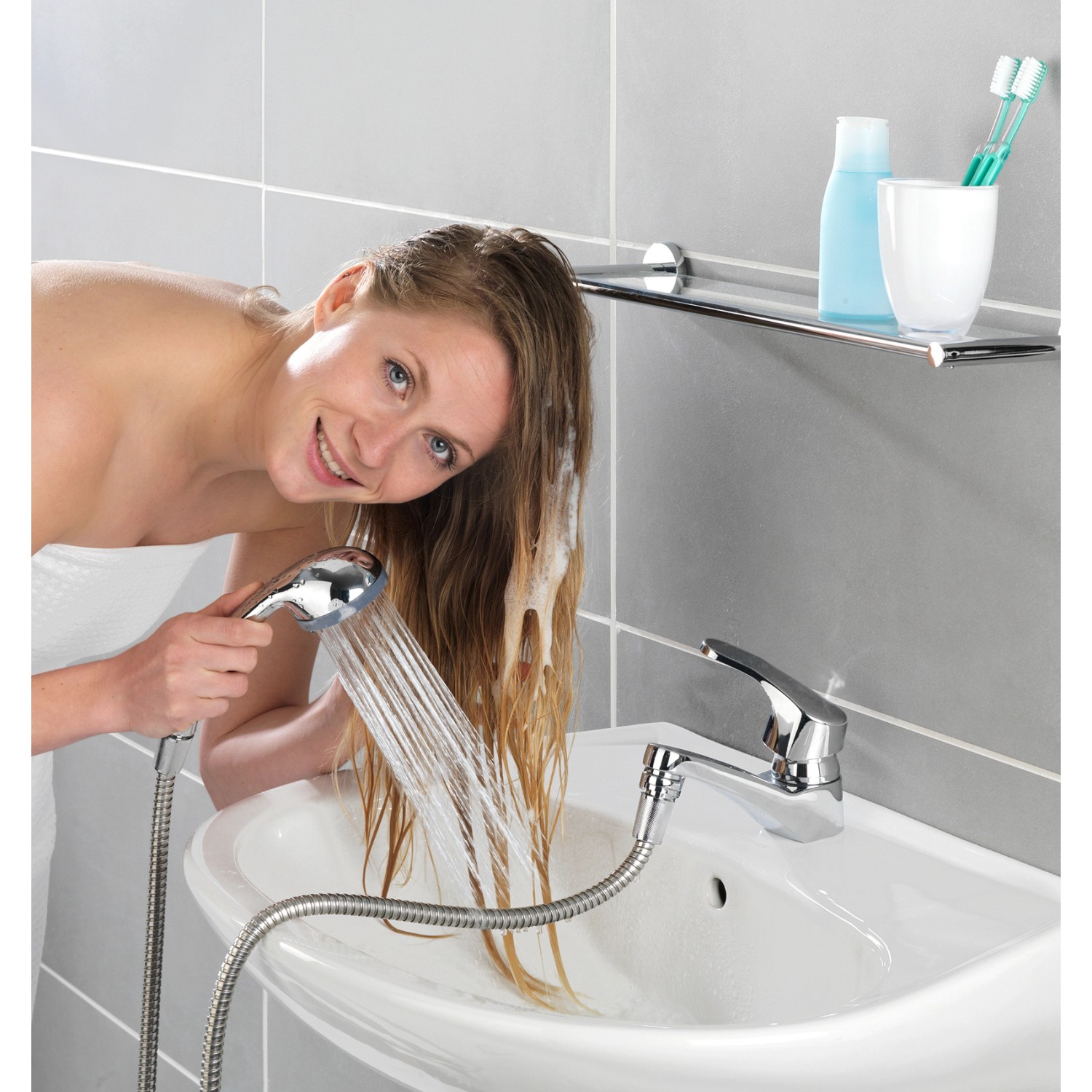 Donna che usa la doccetta per lavabo Wenko cromata per lavarsi i capelli nel lavandino.