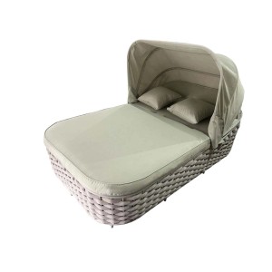 Lettino intrecciato con baldacchino e cuscini, ideale per giardino o terrazza.